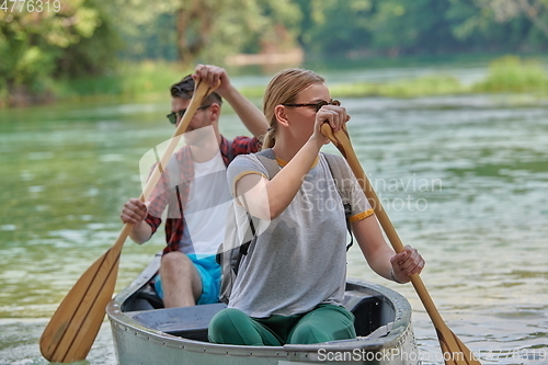 Image of friends are canoeing in a wild river