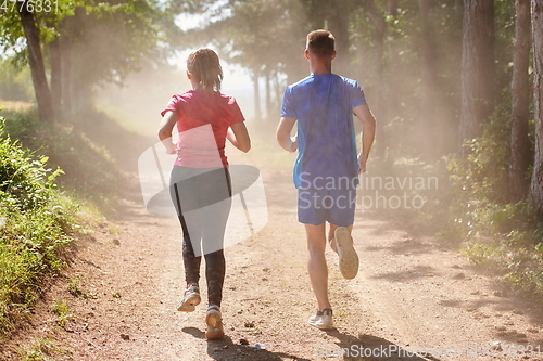 Image of couple enjoying in a healthy lifestyle while jogging on a country road