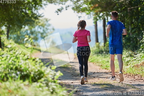 Image of couple enjoying in a healthy lifestyle while jogging on a country road