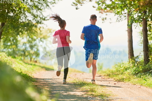 Image of couple enjoying in a healthy lifestyle while jogging on a country road