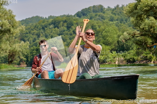 Image of friends are canoeing in a wild river