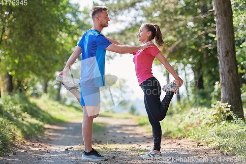 Image of couple enjoying in a healthy lifestyle warming up and stretching before jogging