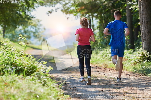 Image of couple enjoying in a healthy lifestyle while jogging on a country road