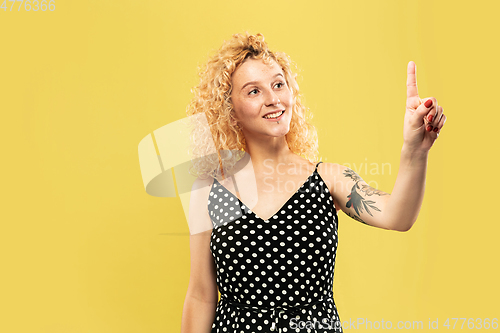 Image of Caucasian young woman\'s half-length portrait on yellow background