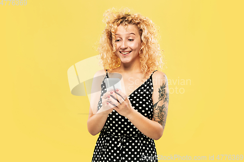 Image of Caucasian young woman\'s half-length portrait on yellow background