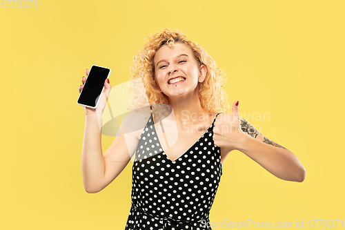 Image of Caucasian young woman\'s half-length portrait on yellow background