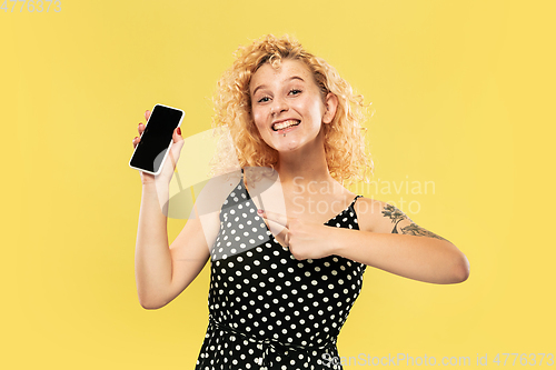 Image of Caucasian young woman\'s half-length portrait on yellow background
