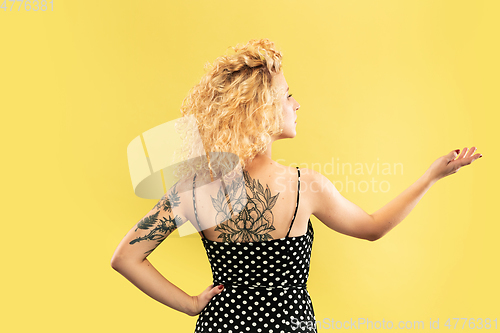 Image of Caucasian young woman\'s half-length portrait on yellow background