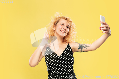 Image of Caucasian young woman\'s half-length portrait on yellow background