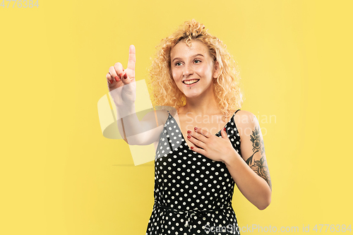 Image of Caucasian young woman\'s half-length portrait on yellow background