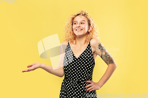 Image of Caucasian young woman\'s half-length portrait on yellow background