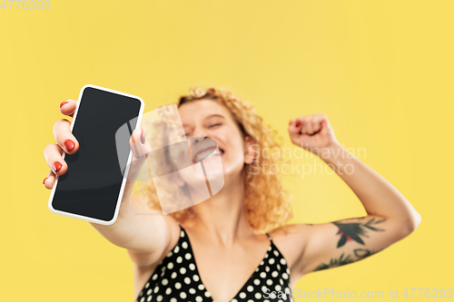 Image of Caucasian young woman\'s half-length portrait on yellow background