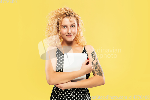 Image of Caucasian young woman\'s half-length portrait on yellow background