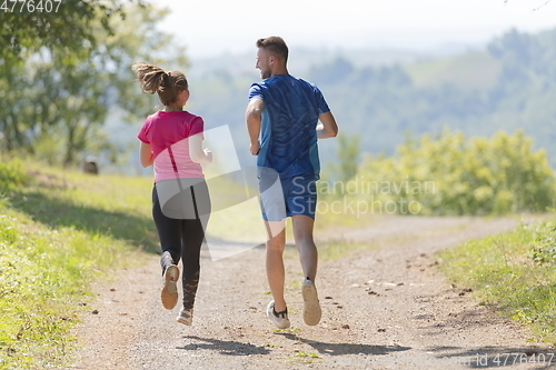 Image of couple enjoying in a healthy lifestyle while jogging on a country road