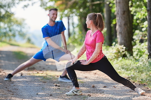 Image of couple enjoying in a healthy lifestyle warming up and stretching before jogging