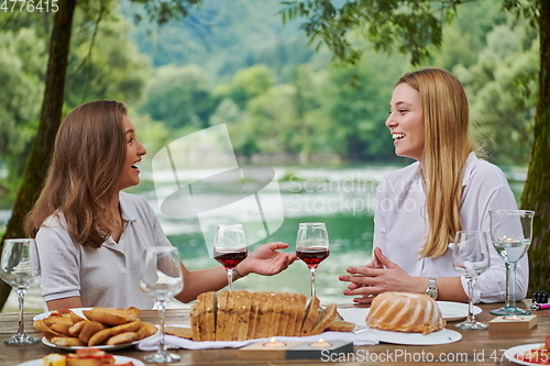 Image of girlfriends having picnic french dinner party outdoor