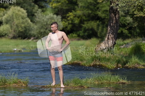 Image of a young man stands by the river