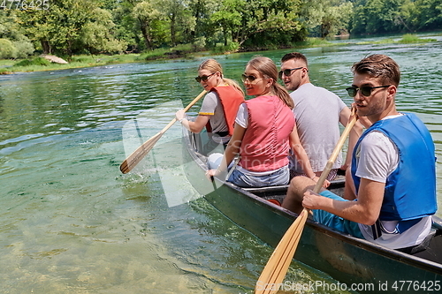 Image of Group adventurous explorer friends are canoeing in a wild river