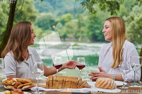 Image of girlfriends having picnic french dinner party outdoor