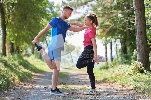 Image of couple enjoying in a healthy lifestyle warming up and stretching before jogging