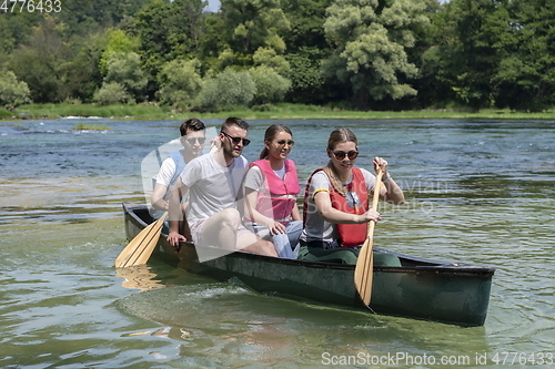 Image of Group adventurous explorer friends are canoeing in a wild river