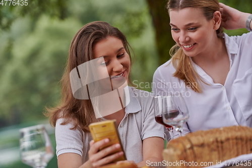 Image of girlfriends having picnic french dinner party outdoor