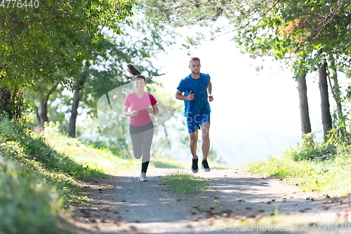 Image of couple enjoying in a healthy lifestyle while jogging on a country road