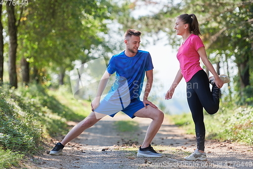 Image of couple enjoying in a healthy lifestyle warming up and stretching before jogging