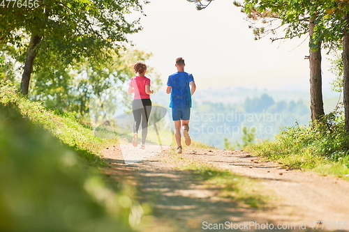 Image of couple enjoying in a healthy lifestyle while jogging on a country road