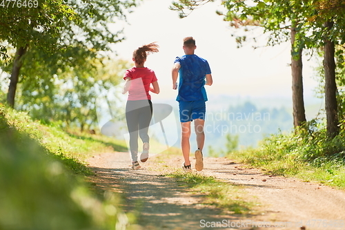 Image of couple enjoying in a healthy lifestyle while jogging on a country road