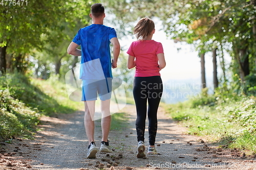 Image of couple enjoying in a healthy lifestyle while jogging on a country road