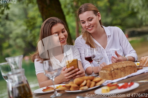 Image of girlfriends having picnic french dinner party outdoor