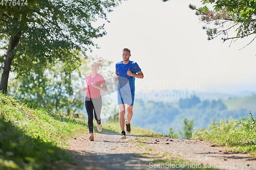 Image of couple enjoying in a healthy lifestyle while jogging on a country road