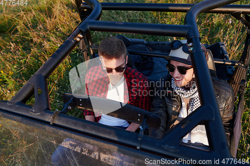 Image of two young happy excited men enjoying beautiful sunny day while driving a off road buggy car