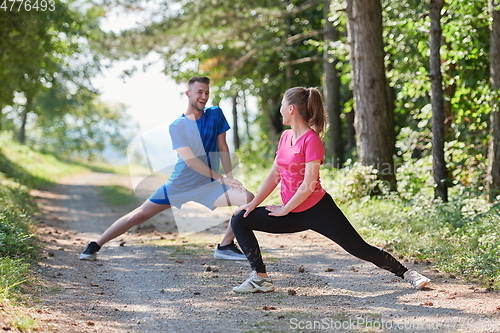 Image of couple enjoying in a healthy lifestyle warming up and stretching before jogging