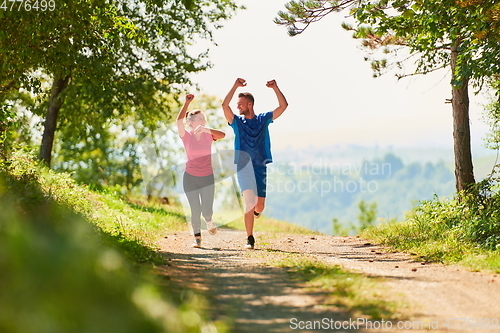 Image of couple enjoying in a healthy lifestyle while jogging on a country road