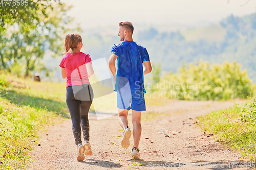 Image of couple enjoying in a healthy lifestyle while jogging on a country road