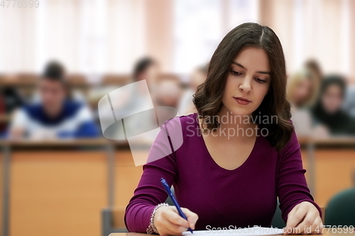 Image of girl sitting in an amphitheater and talking to her colleagues