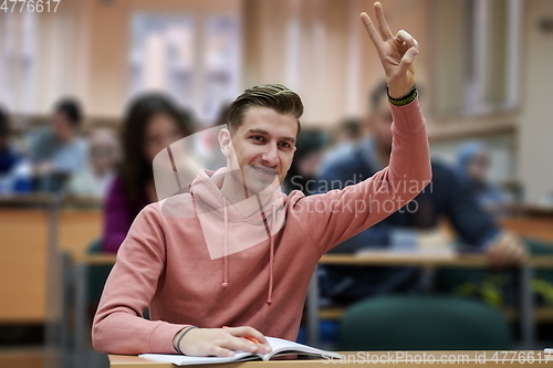 Image of The student raises his hands asking a question in class in college