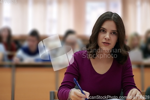 Image of girl sitting in an amphitheater and talking to her colleagues