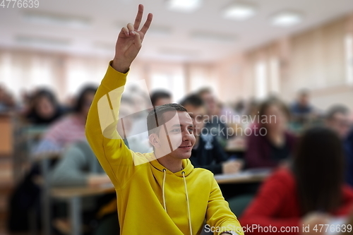 Image of The student raises his hands asking a question in class in college