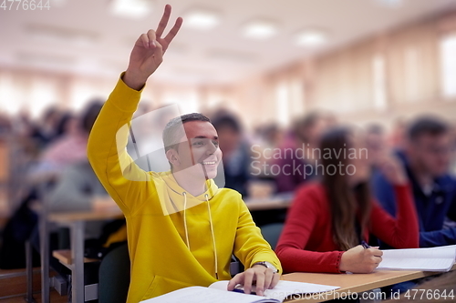 Image of The student raises his hands asking a question in class in college