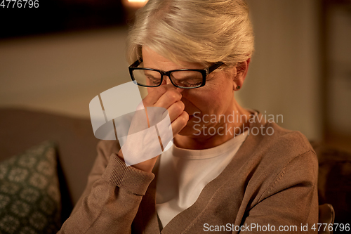 Image of tired senior woman in glasses at home at night