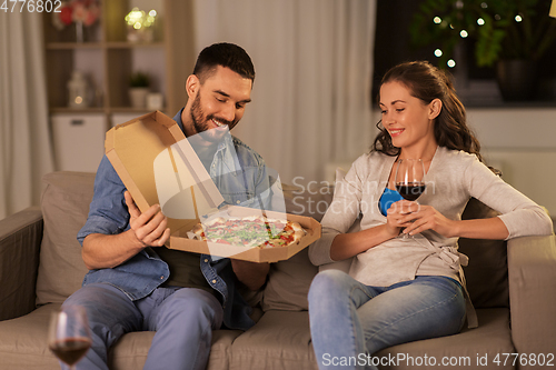 Image of happy couple eating takeaway pizza at home