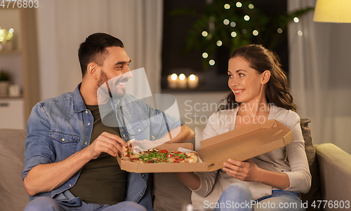 Image of happy couple eating takeaway pizza at home