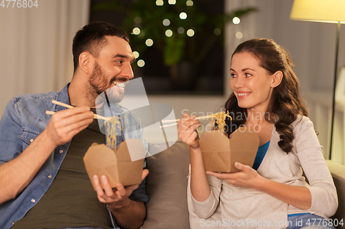 Image of happy couple eating takeaway noodles at home