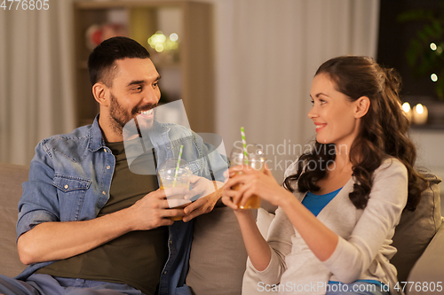 Image of happy couple drinking takeaway juice at home