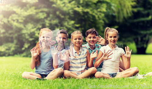 Image of group of happy kids waving hands outdoors
