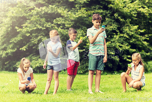 Image of kids with smartphones playing game in summer park