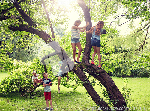 Image of happy kids climbing up tree in summer park